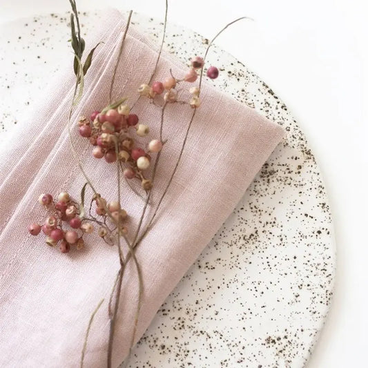 Pink napkin with berries and a branch on a speckled surface