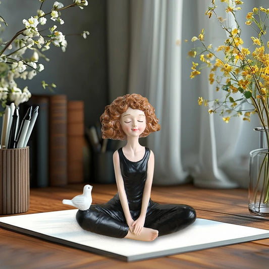 Decorative figurine of a woman meditating with a bird on a wooden table.