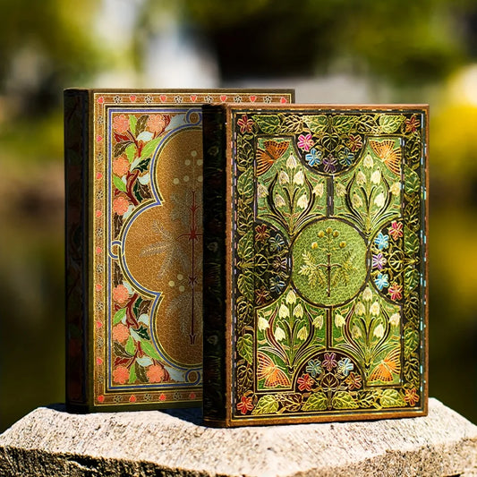 Decorative book with intricate designs on a stone surface with a blurred natural background
