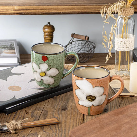 Two floral mugs on a wooden surface with decorative items.