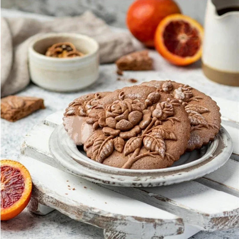 Decorative cookies on a plate with blood oranges and cinnamon sticks on a rustic surface