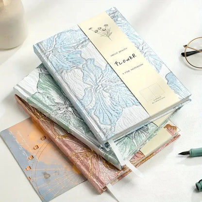 Stack of notebooks with floral designs on a white surface
