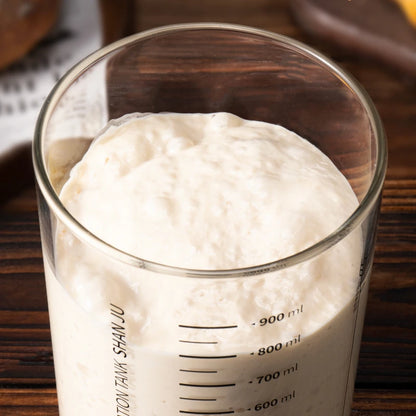 Glass measuring cup filled with a white substance on a wooden surface