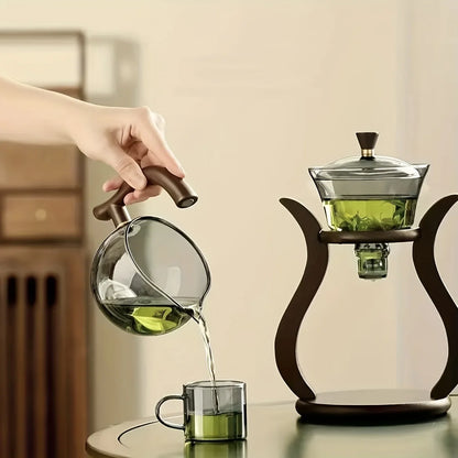 Person pouring green liquid from a glass pitcher into a cup with a wooden handle.