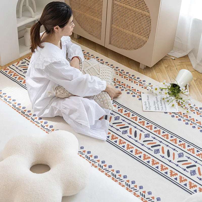 Woman sitting on a decorative rug with a geometric pattern in a room.