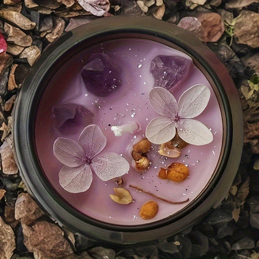 Candle with flowers and stones in a container on a stone surface