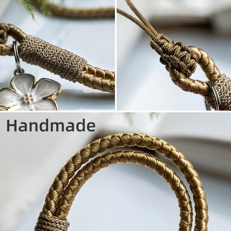 Close-up of a handmade braided keychain with a floral pendant on a light background.