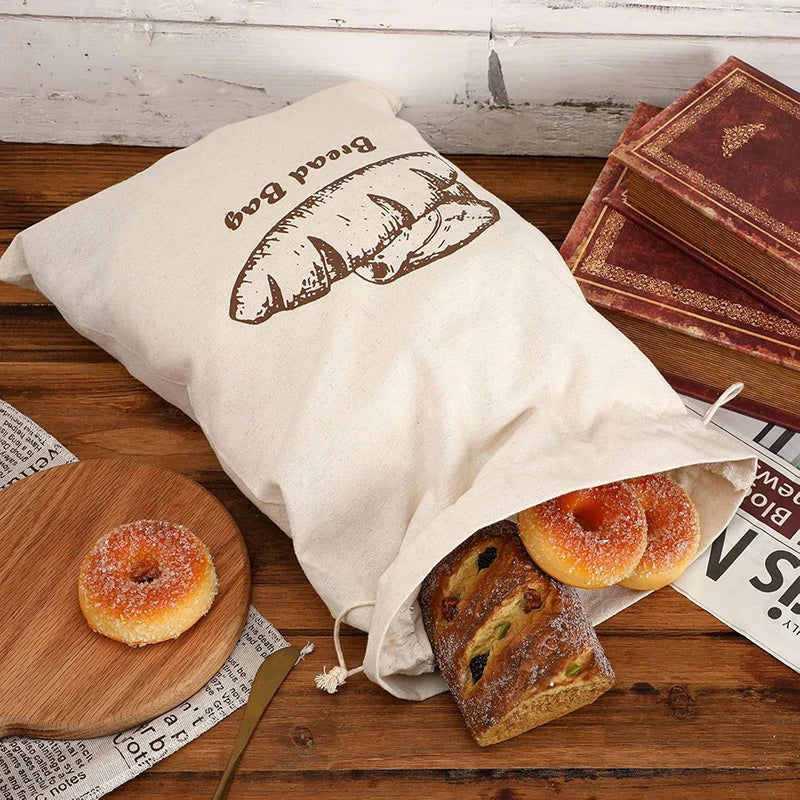 Fabric bread bag with bread and donuts on a wooden table