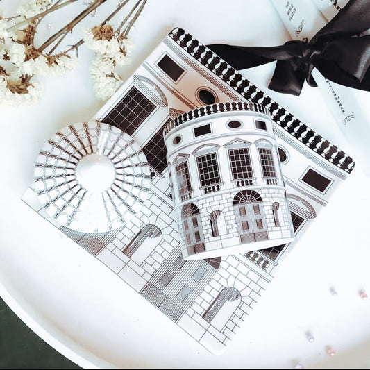 Decorative paper with architectural designs and a black ribbon on a white surface.