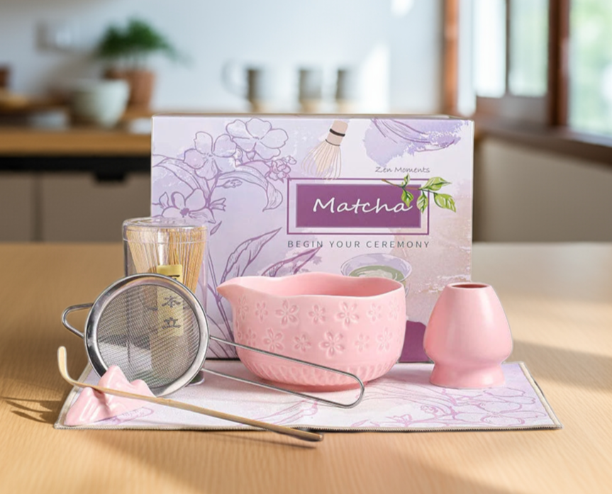 Matcha tea set with a pink bowl, whisk, and matching box on a wooden table.