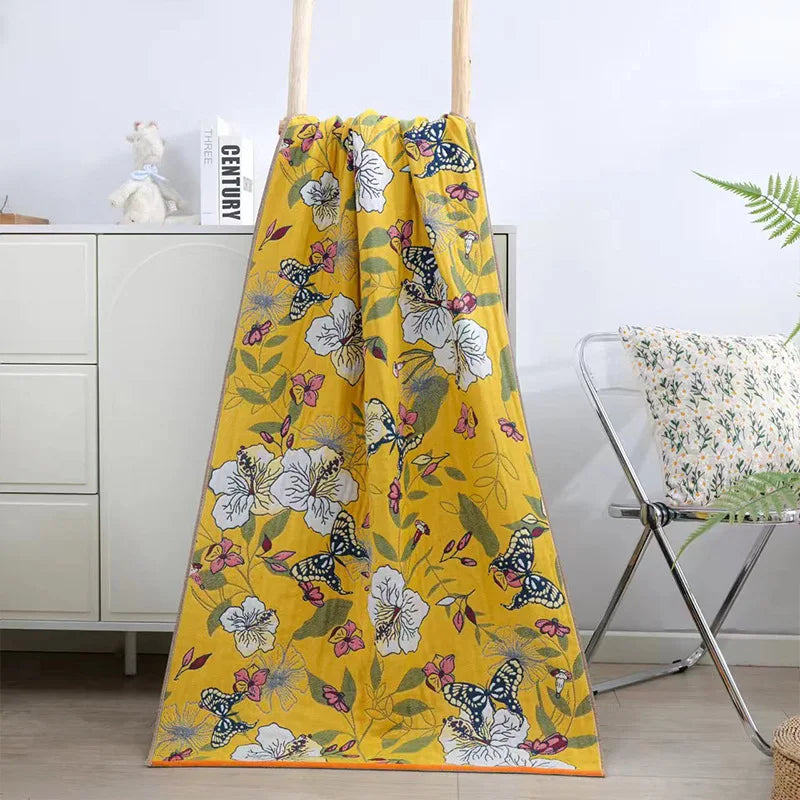 Yellow floral and butterfly patterned blanket draped over a chair in a room.