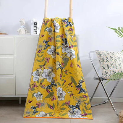 Yellow floral and butterfly patterned blanket draped over a chair in a room.