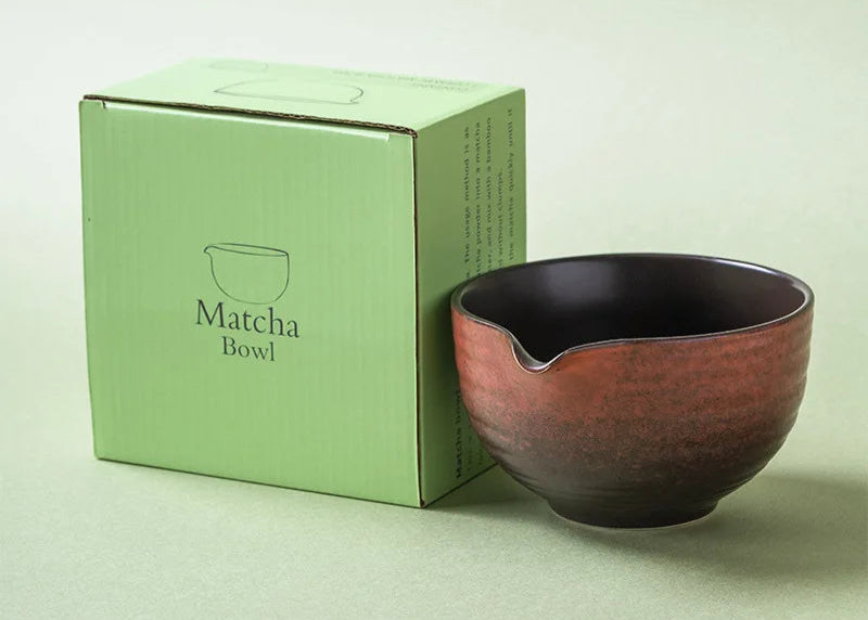 Ceramic matcha bowl next to its packaging box on a light green background
