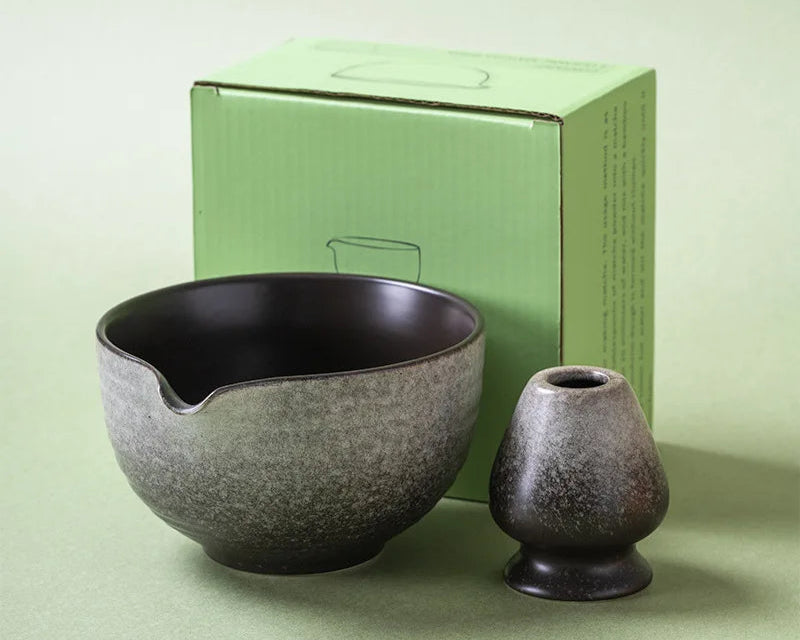 Two ceramic items, a bowl and a small vase, in front of a green box on a light green background.