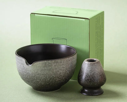 Two ceramic items, a bowl and a small vase, in front of a green box on a light green background.