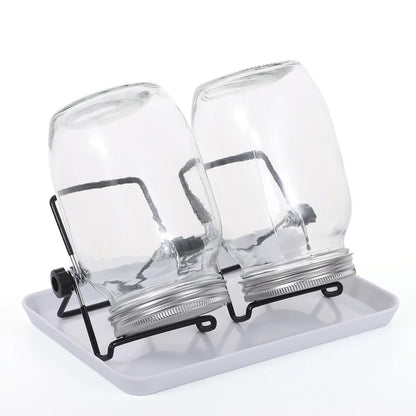 Two clear glass jars with metal lids on a white tray against a white background