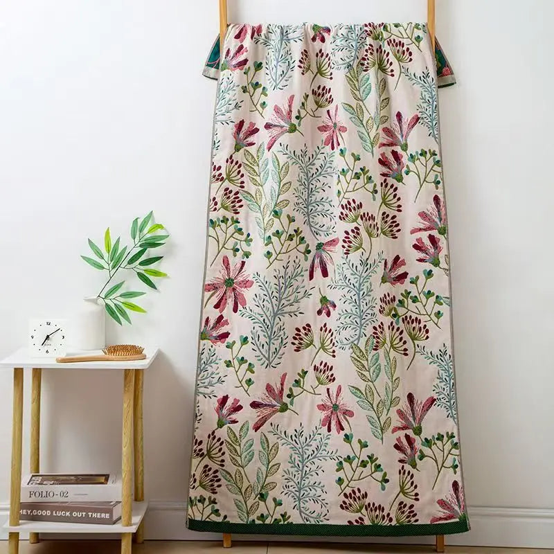 Floral patterned blanket draped over a wooden rack against a white wall.