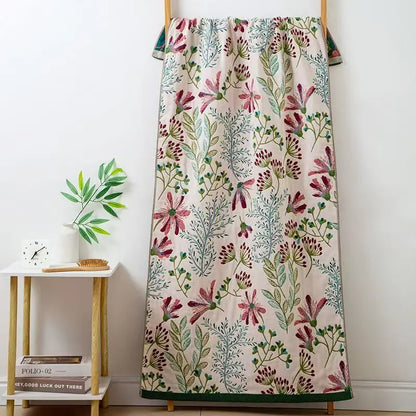Floral patterned blanket draped over a wooden rack against a white wall.