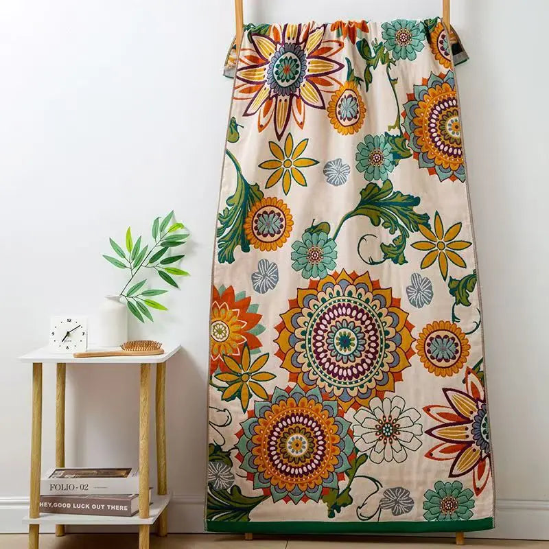 Colorful floral-patterned towel hanging on a wooden hanger against a white wall.