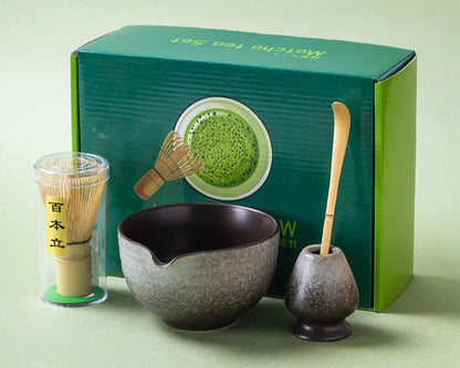 Tea-making set with a bowl, whisk, and scoop in front of a green box on a light green background