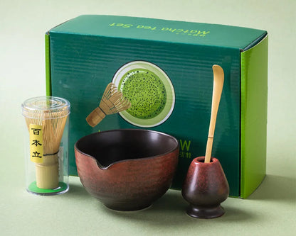 Matcha tea set with bowl, whisk, and holder in front of a green box on a light green background