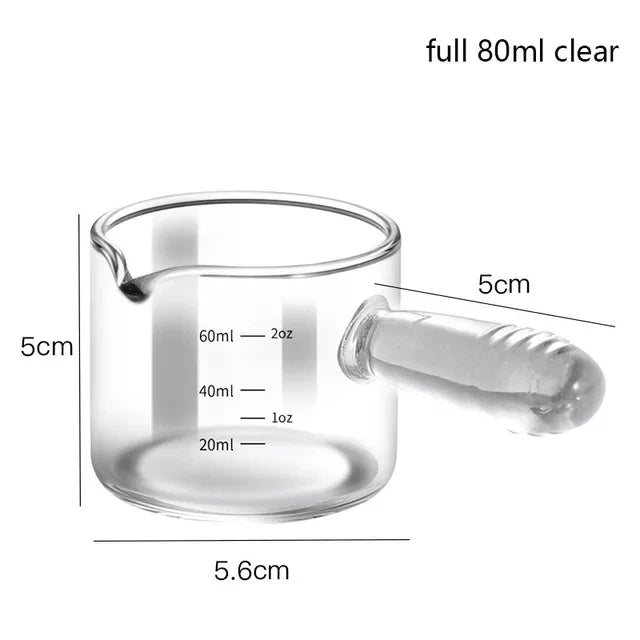 Clear glass measuring cup with handle and measurement markings on a white background