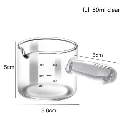 Clear glass measuring cup with handle and measurement markings on a white background