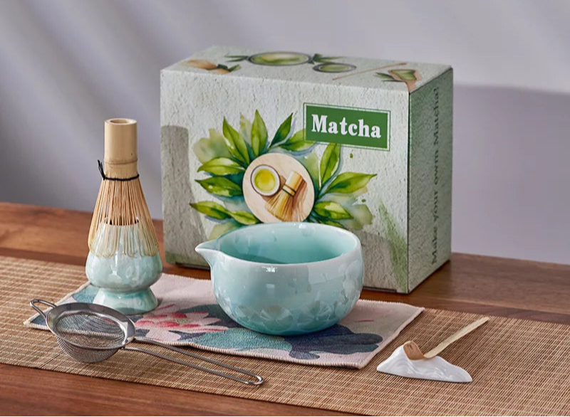 Matcha tea set with a box labeled 'Matcha' on a wooden table.