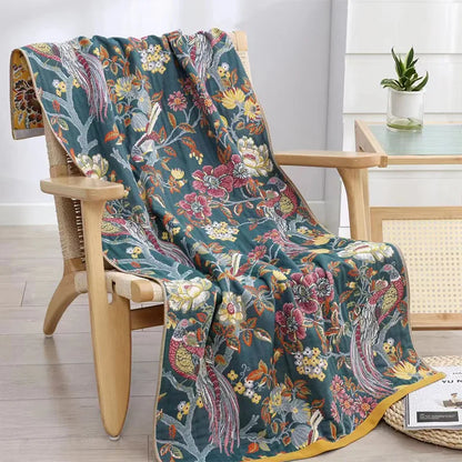 Floral patterned blanket draped over a wooden chair in a room with a table and plant.