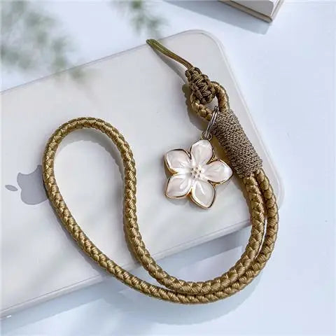 Gold braided keychain with a white flower charm on a white surface