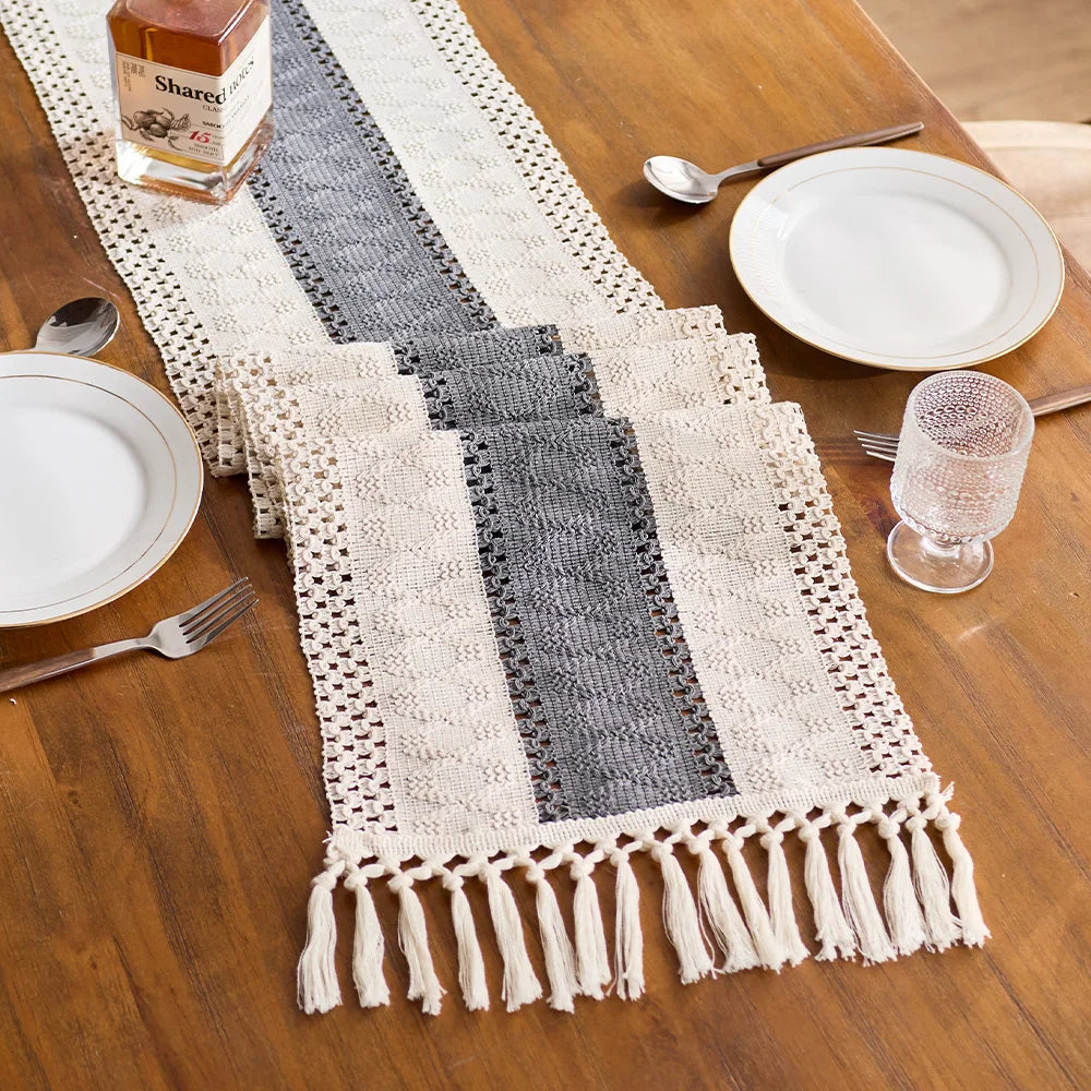 Set of woven table runners in gray and white on a wooden table with plates and glasses.