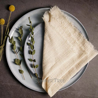 Beige napkin on a gray plate with greenery and flowers on a brown background, featuring 'SummerTree' branding.