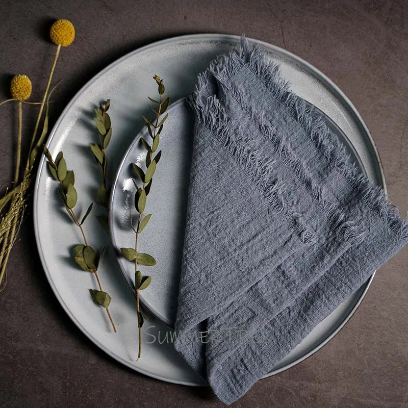 Gray napkin on a plate with greenery and a fork, on a brown surface.