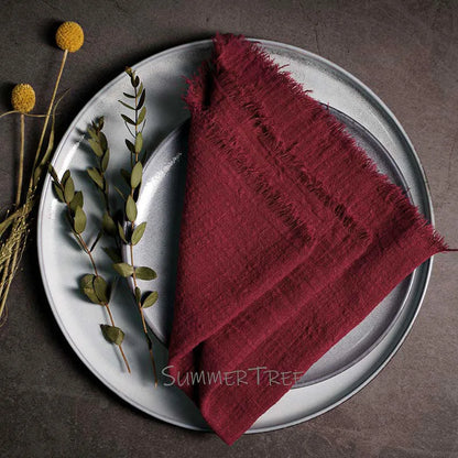 Red napkin on a gray plate with greenery, on a dark surface.