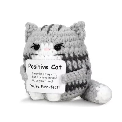 Crocheted cat plush toy with a sign reading 'Positive Cat' on a white background