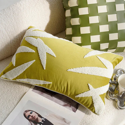 Green pillow with white leaf patterns on a couch next to a coffee cup and magazine.