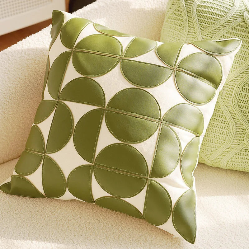 Decorative pillow with green leaf pattern on a beige couch