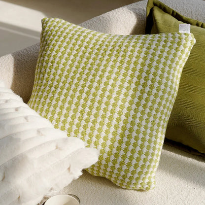 Green and white patterned pillow on a beige sofa