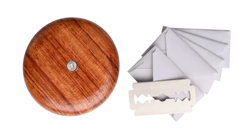 Wooden grinder with razor blades and paper on a white background