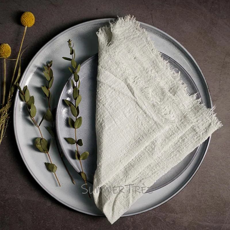 White textured fabric on a gray plate with greenery on a brown background