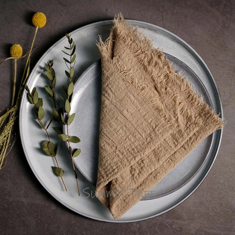 Beige napkin on a gray plate with greenery on a dark surface