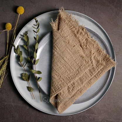Beige napkin on a gray plate with greenery on a dark surface