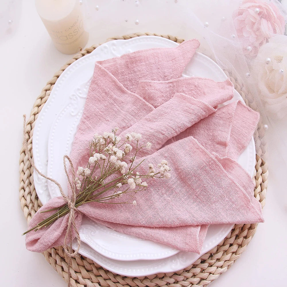 Pink folded fabric on a white plate with small flowers, placed on a woven mat.