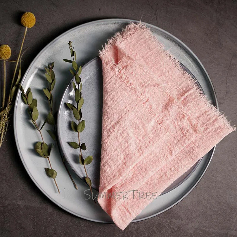 Pink napkin on a gray plate with greenery and flowers on a dark surface, featuring 'Summer Tree' branding.