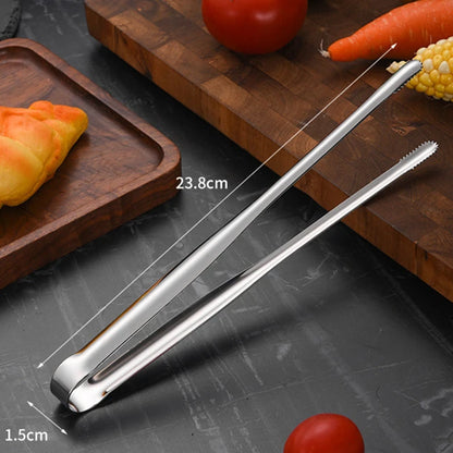 Metal tongs on a cutting board with vegetables and a piece of bread.