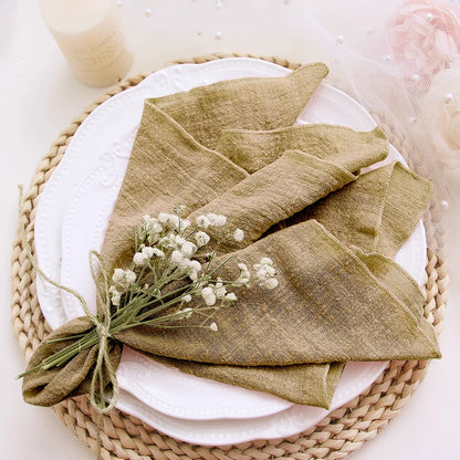 Green folded napkin with baby's breath on a white plate with a woven placemat.