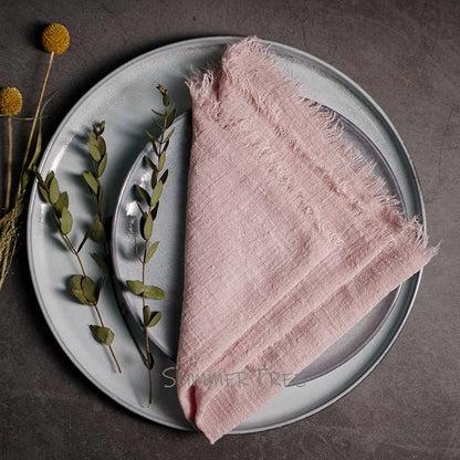 Pink napkin on a gray plate with greenery on a dark surface