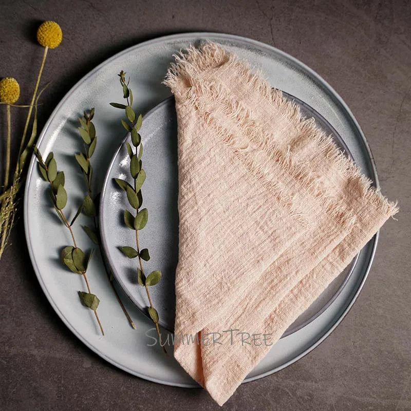 Beige napkin on a gray plate with greenery, on a brown surface.