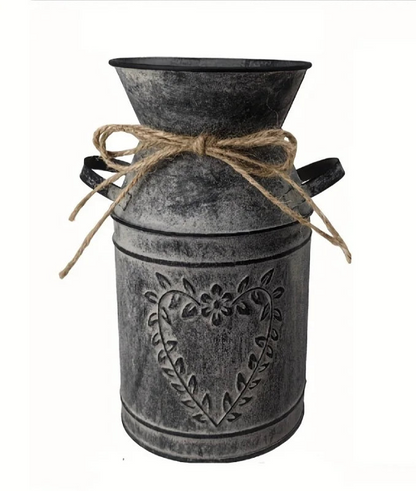 Decorative metal milk churn with heart design and twine bow on a white background