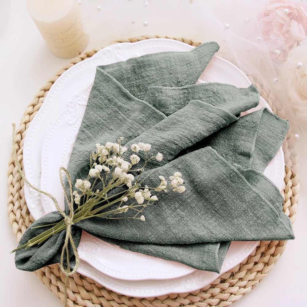 Green folded napkin on a white plate with baby's breath flowers, placed on a woven mat.